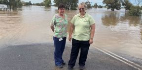Andrea and Sandra standing on road next to flood waters