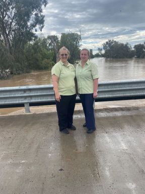 Andrea and Sandra standing on bridge next to flood waters