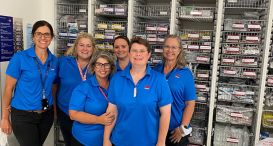 Dubbo’s DeliverEASE team of six, smiling for the camera in one of Dubbo Base Hospital’s newly reorganised medical consumables storerooms.